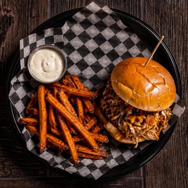Pulled pork sandwich with melted cheese and BBQ sauce, sweet potato fries, and ranch dip.